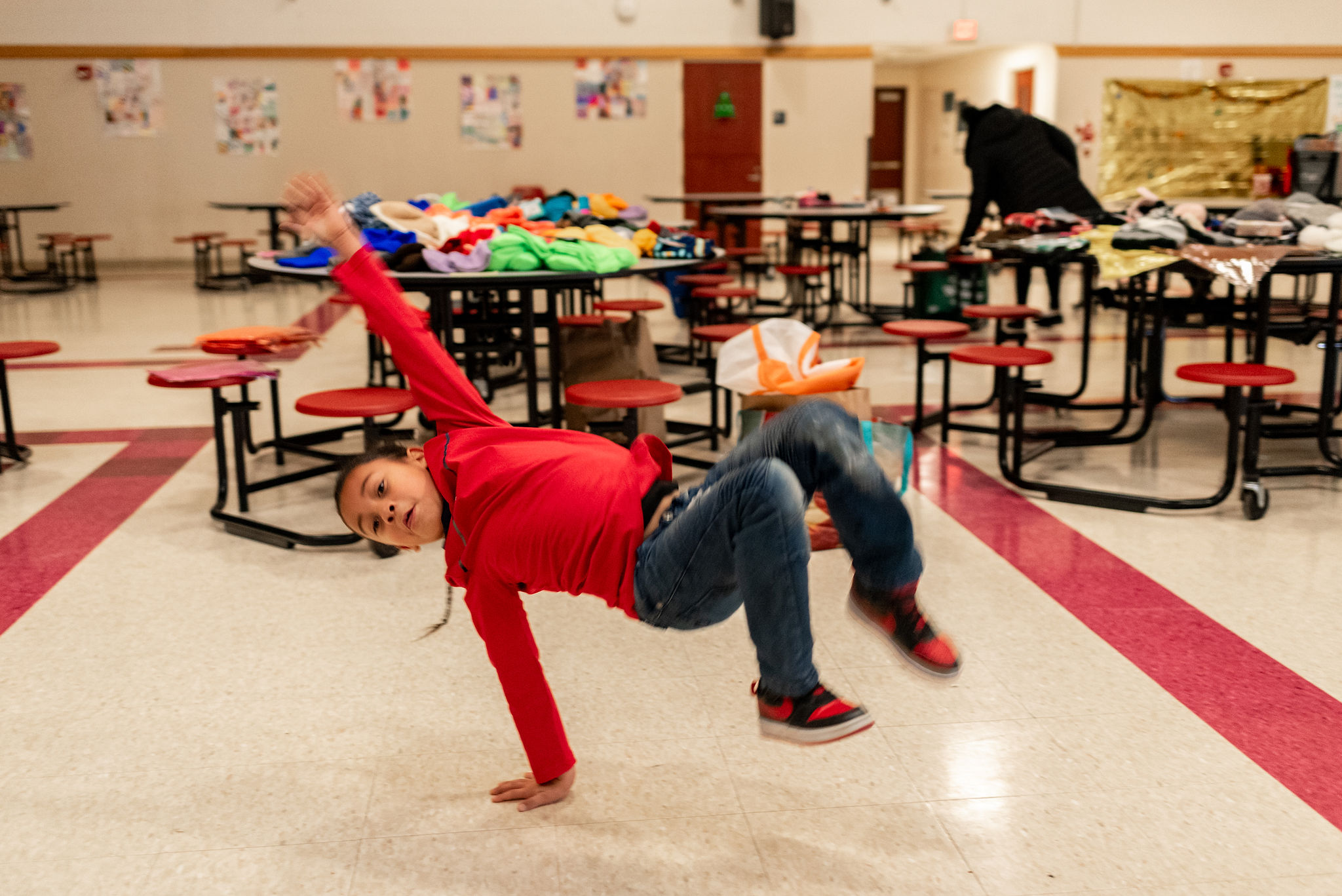 An elementary school aged girl in a still photo of her doing an acrobatic flip caught in mid-air.